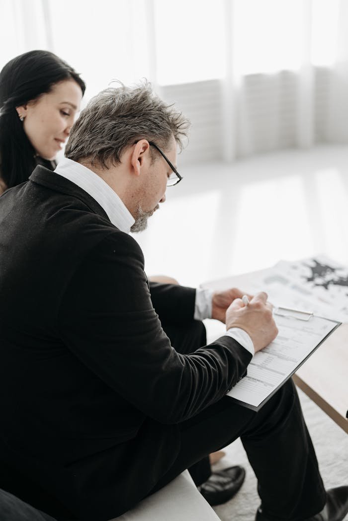 Man and woman in business attire signing a document indoors.